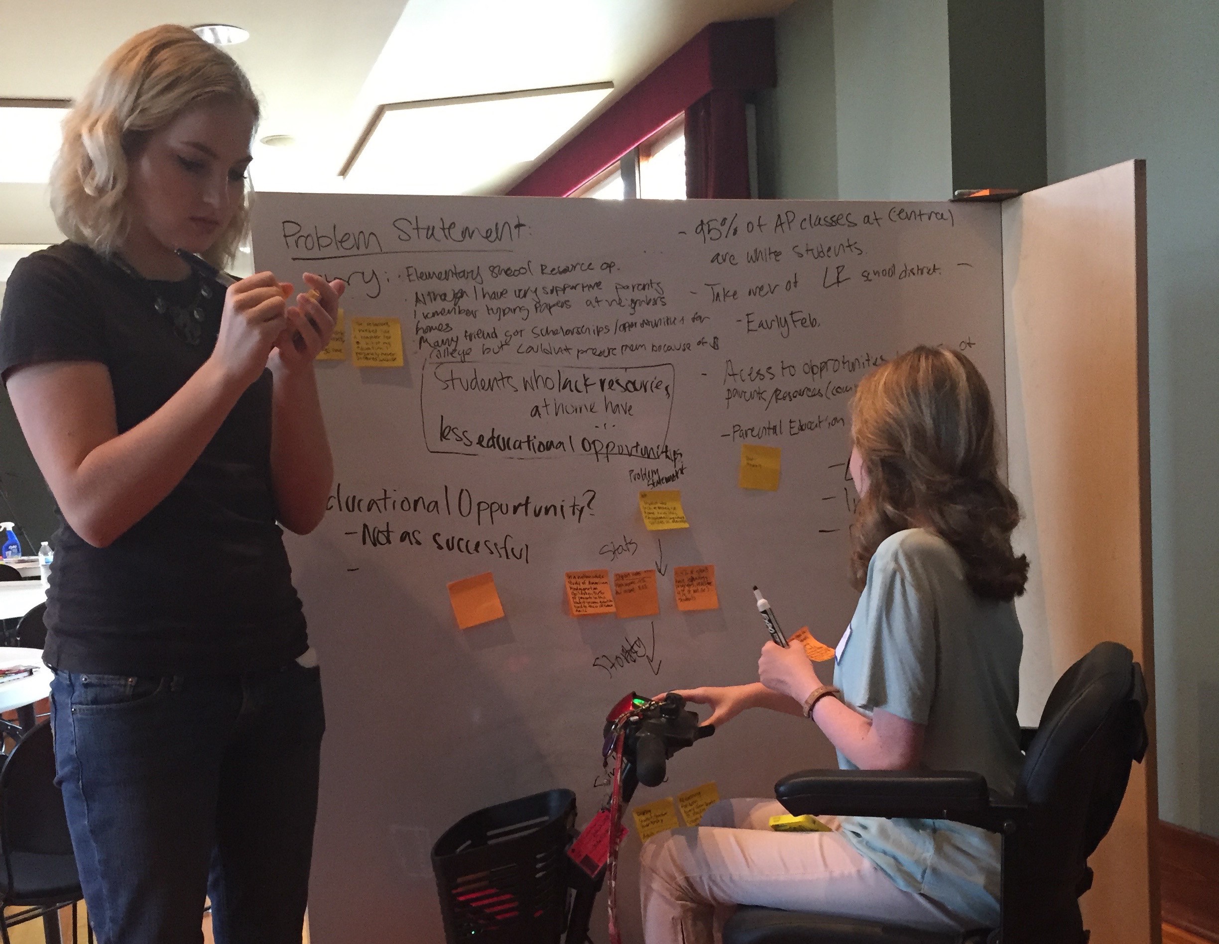 Noble Impact scholars Greta Kresse and Olivia Fitzgibbon white board at an event about challenging the existing opportunity gap in education.